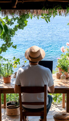 Man works remotely on laptop, seaside patio, ocean view