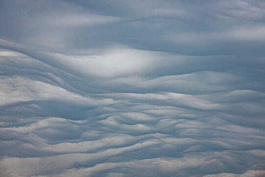 Striking undulatus asperatus clouds roll dramatically across the sky above silhouettes of leafless winter trees, creating a surreal and moody atmosphere. Includes copy space.