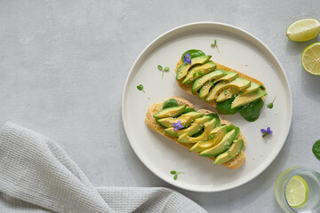 Delitious avocado toast shot from above on a minimal white plate, topped wih mycrogreens and sesame...