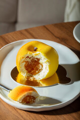 Mousse cake with peach filling covered with velvet glaze and a cup of latte on a table in a cafe.