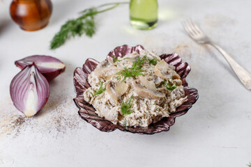 A bowl of mushroom salad with red onion and dill.