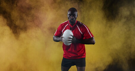 African American man holding rugby ball, wearing red jersey, looking determined