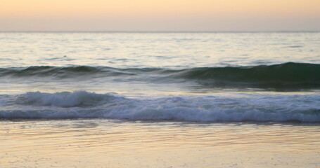 Obraz premium Sunset over serene beach with waves gently crashing, creating peaceful scene