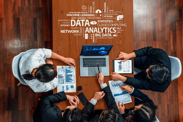 A diverse group of professionals collaborates in a vibrant meeting, analyzing data on laptops and documents, showcasing modern business analytics and teamwork strategies. Amity