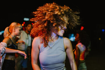 Young woman dancing at night with friends at concert or party