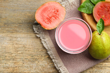 Refreshing guava juice and fresh fruits on wooden table, flat lay. Space for text