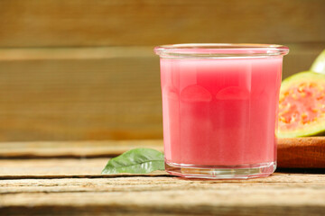 Refreshing guava juice and fresh fruits on wooden table, closeup. Space for text