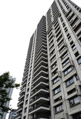 Fototapeta premium Imposing concrete facade of a high-rise apartment building, stark white background, urban scene, low angle