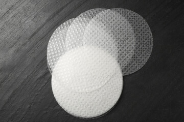 Edible rice paper sheets on dark textured table, flat lay