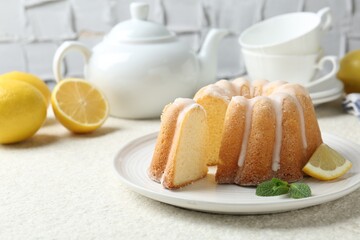 Delicious lemon cake with glaze and mint on light textured table, closeup