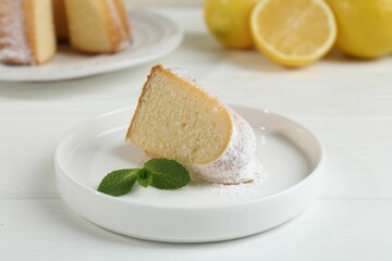 Piece of delicious lemon cake with powdered sugar and mint on white wooden table, closeup