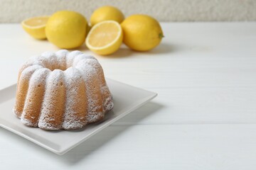 Delicious lemon cake with powdered sugar on white wooden table, closeup. Space for text