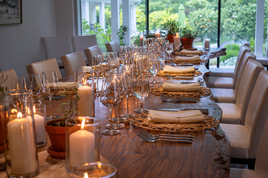 Untouched wooden dinner table served with glassware, silverware and candle decorations for gathering and celebration at a small cozy rustic winery restaurant, selective focus.