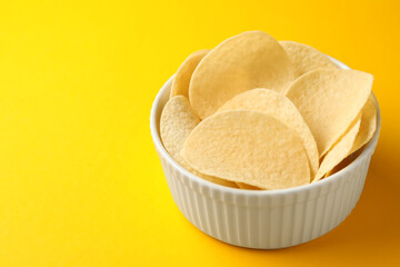 Tasty potato chips on yellow background, closeup. Space for text