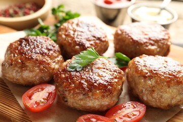 Delicious patties with parsley and tomatoes on table, closeup