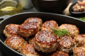 Delicious patties in baking dish on table, closeup