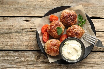 Delicious patties, parsley, tomatoes and sauce on wooden table, top view. Space for text