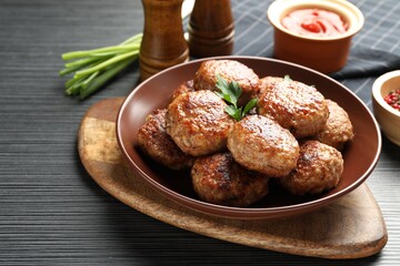 Delicious patties and spices on black textured table, closeup