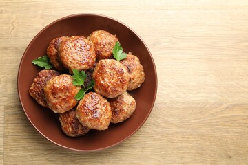 Delicious patties with parsley on wooden table, top view. Space for text