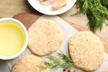 Many uncooked patties and spices on wooden table, flat lay