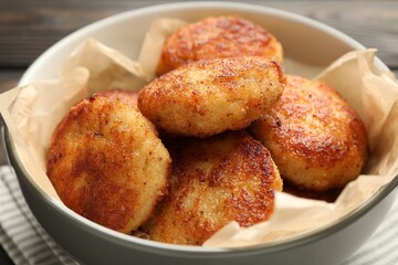 Tasty patties in bowl on table, closeup