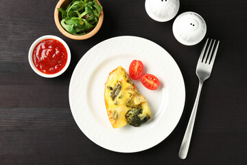 Tasty vegetable casserole served on black wooden table, flat lay