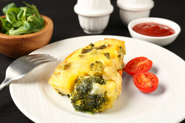 Tasty vegetable casserole and tomato on black table, closeup