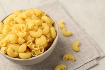 Raw horns pasta in bowl on gray table, closeup. Space for text