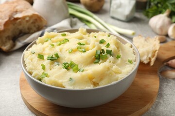 Delicious mashed potato with green onions served on grey table, closeup