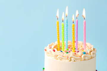 Delicious bento cake with colorful sprinkles and burning candles on light background, closeup. Space for text
