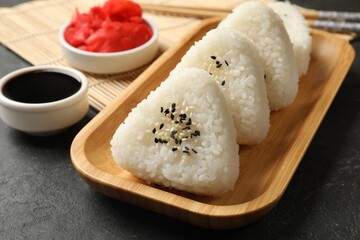 Tasty onigiri (Japanese rice balls) served on black table, closeup