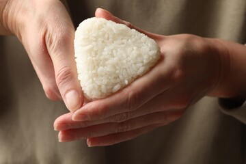 Woman with tasty onigiri (Japanese rice ball), closeup
