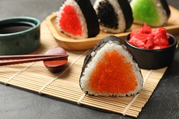 Tasty tobiko onigiri (Japanese rice balls) served on black table, closeup