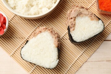 Tasty onigiri (Japanese rice balls) with tuna served on wooden table, flat lay