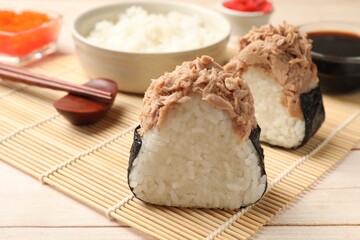 Tasty onigiri (Japanese rice balls) with tuna served on wooden table, closeup