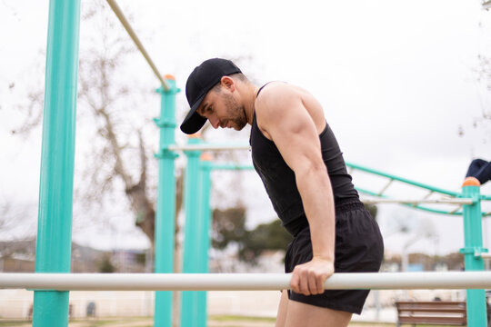 Athlete performing dip exercise in outdoor workout area.