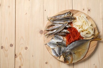 Many different dried fish snacks on wooden table, top view. Space for text