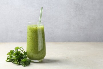 Healthy parsley smoothie in glass and leaves on light textured table against grey background. Space for text