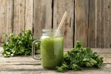 Healthy parsley smoothie in mason jar and leaves on wooden table, closeup