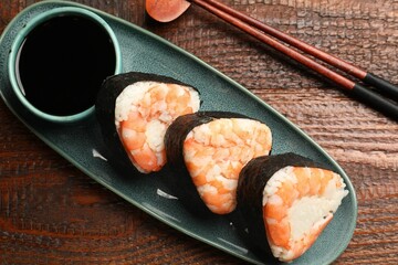 Tasty onigiri (Japanese rice balls) with shrimps served on wooden table, flat lay