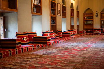 Traditional Omani Majlis Seating with Colorful Cushions and Bookshelves in Nizwa Fort, Oman - Authentic Arabian Interior Design and Decor