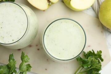 Healthy parsley drink in glasses, leaves and apples on table, flat lay