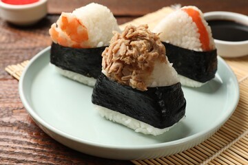 Tasty onigiri (Japanese rice balls) served on wooden table, closeup