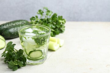 Healthy drink with parsley, cucumbers and celery on light table, space for text