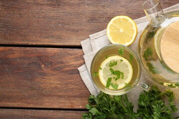 Healthy parsley tea with lemon slices on wooden table, flat lay and space for text. Detox drink