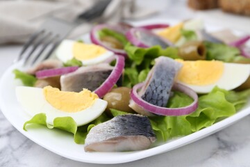 Delicious salad with herring, egg and vegetables on white marble table, closeup