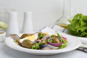 Delicious salad with herring, egg, mustard and vegetables on white tiled table, closeup