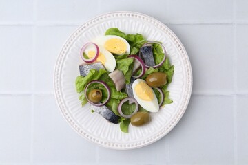 Delicious salad with herring, egg and vegetables on white tiled table, top view