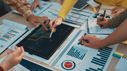 A vibrant team engages in a collaborative meeting focused on data analysis, surrounded by charts, graphs, and technology in a modern office environment. SACTR