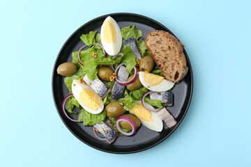 Delicious salad with herring, egg, mustard and vegetables on light blue background, top view